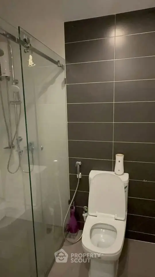 Modern bathroom with glass shower and sleek dark tiles