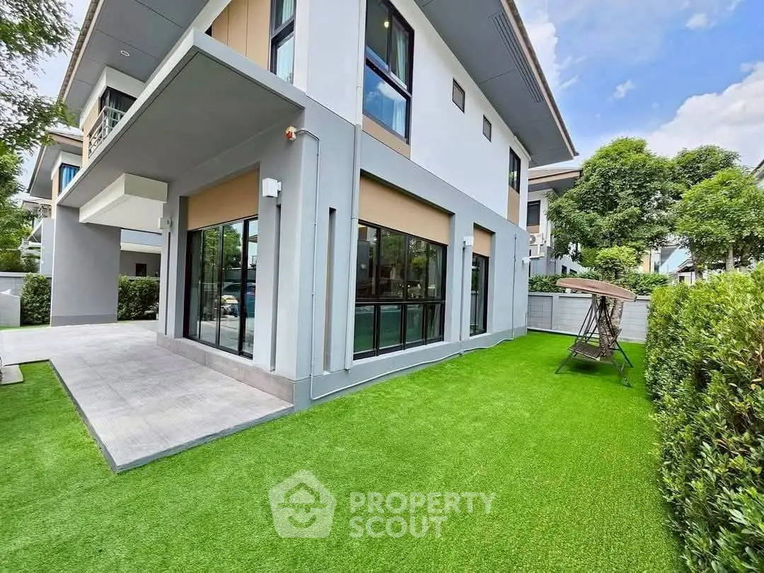 Modern two-story house with lush green lawn and large windows