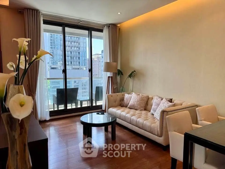 Elegant living room with modern furniture and large windows opening to a balcony with city view.