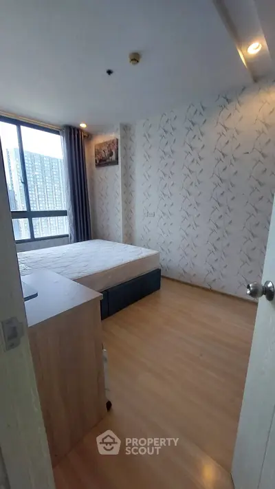 Modern bedroom with large window and stylish wallpaper in a high-rise apartment.