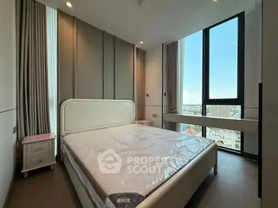 Modern bedroom with large window and city view, featuring elegant decor and natural light.