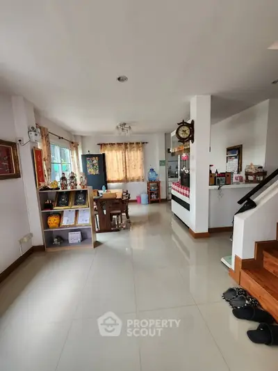 Spacious living room with modern decor and open layout, featuring a cozy dining area and elegant staircase.