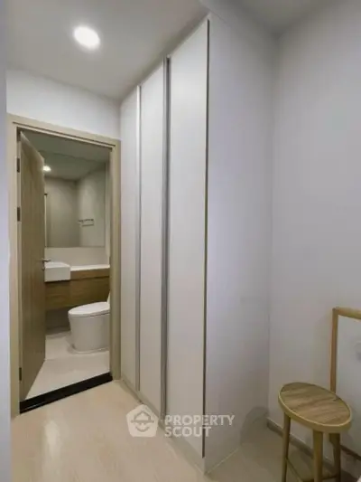 Modern apartment hallway leading to a sleek bathroom with minimalist design.