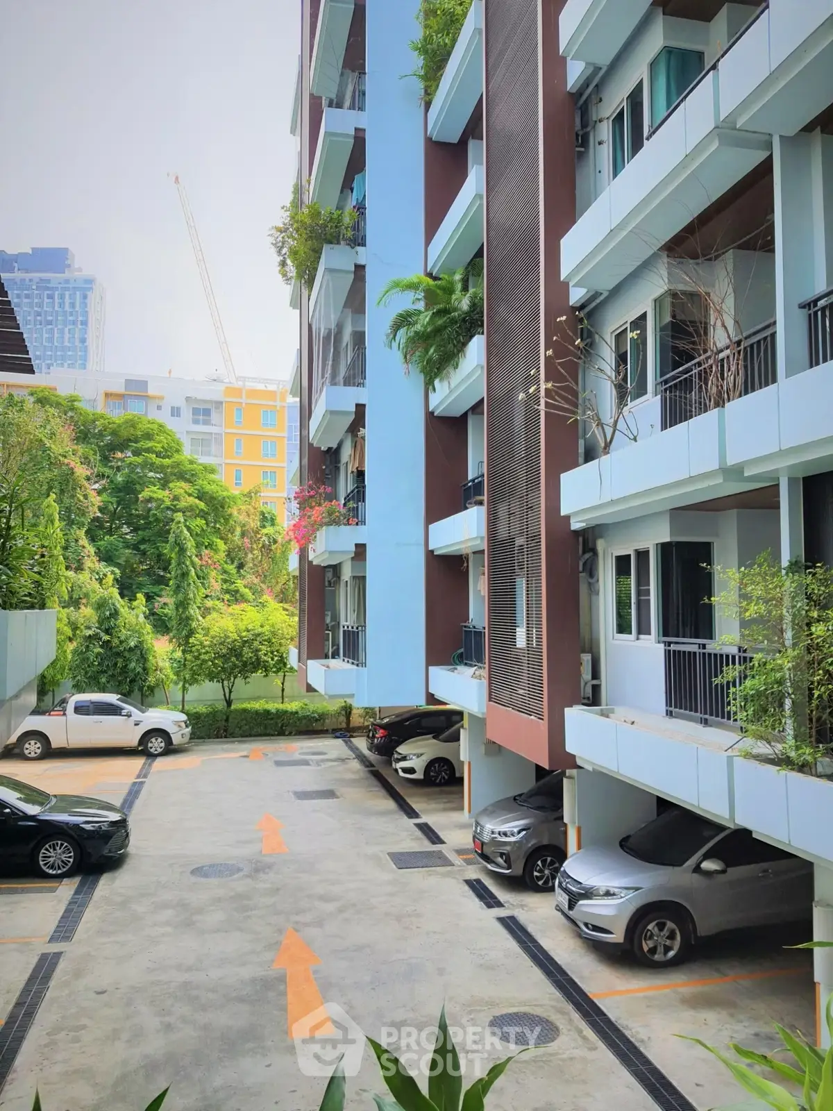 Modern apartment building with parking area and lush greenery
