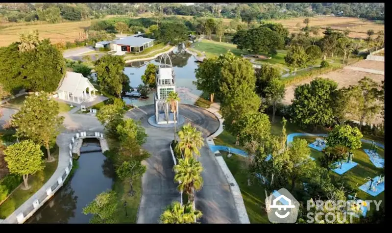 Aerial view of a luxurious estate with a serene water feature, lush landscaping, and multiple buildings, showcasing a tranquil and opulent lifestyle.