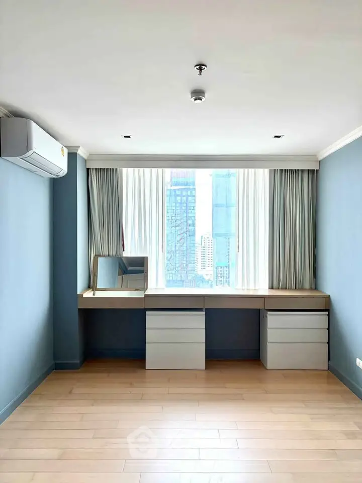 Spacious study room with city view and modern desk setup in high-rise apartment.
