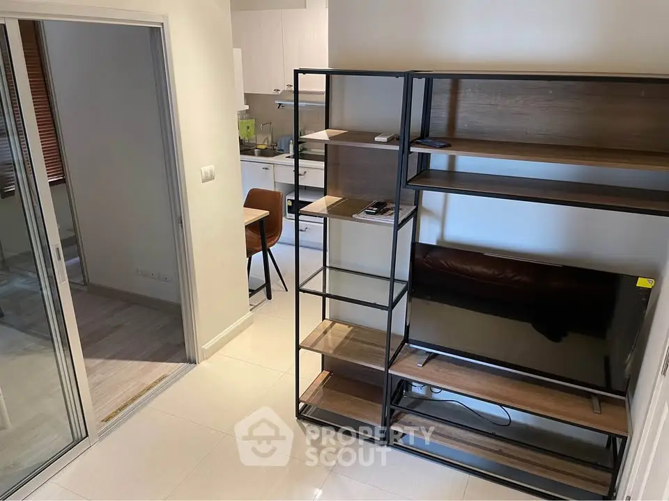 Modern apartment interior with open layout, featuring a sleek kitchen and stylish shelving unit.