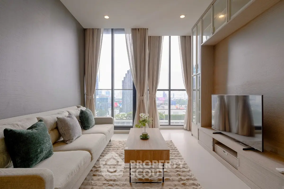 Modern living room with large windows and city view, featuring stylish decor and comfortable seating.