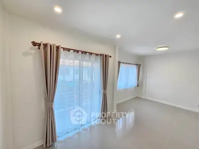 Spacious and bright living room with large windows and elegant curtains
