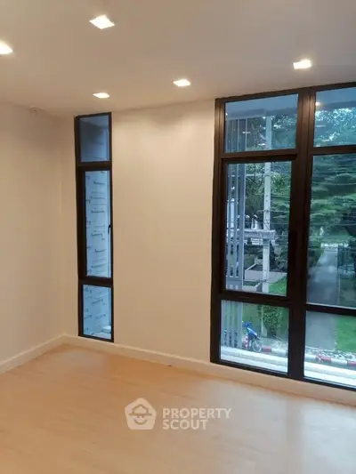 Spacious room with large windows offering serene garden views, perfect for natural light lovers.