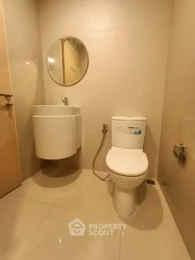 Modern bathroom with sleek fixtures and round mirror, showcasing minimalist design.