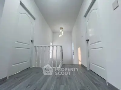Bright hallway with modern flooring and elegant chandelier in a contemporary home.