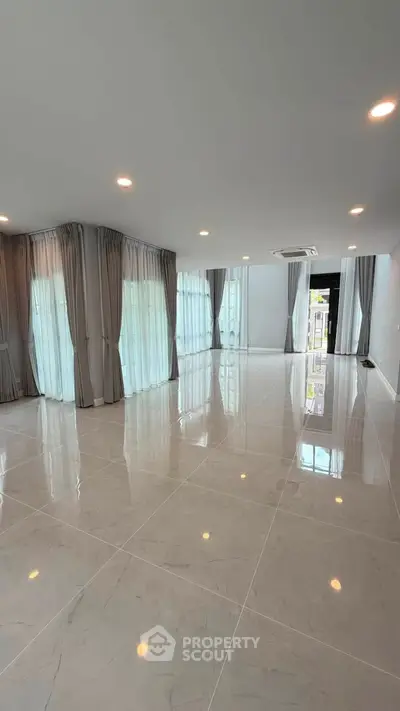 Spacious modern living room with large windows and elegant curtains, perfect for natural light and open living.