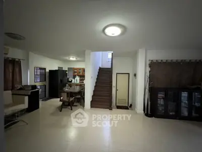 Spacious open-plan living area with dining table and modern kitchen appliances.