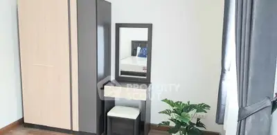 Modern bedroom with wardrobe, vanity, and potted plant in bright natural light.