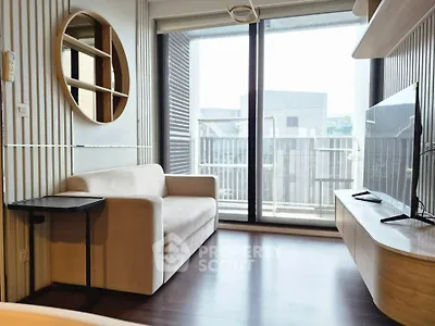 Modern living room with sleek furniture and large windows opening to a balcony with urban view.