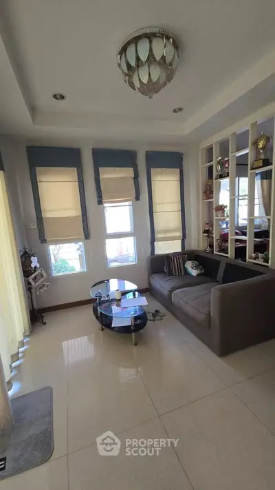 Spacious living room with modern decor and large windows, perfect for relaxation and entertaining.