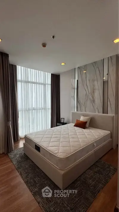 Luxurious bedroom with modern design, featuring a large window and elegant decor.