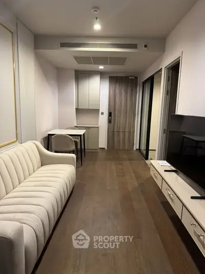 Modern living room with elegant sofa and large TV, featuring sleek wooden flooring and minimalist decor.