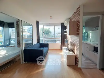 Modern apartment living room with open kitchen and large windows for natural light.
