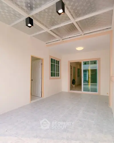Spacious covered patio with modern lighting and tiled flooring, perfect for outdoor relaxation.
