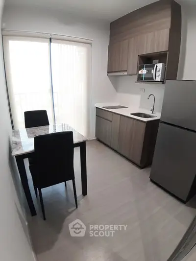 Modern kitchen with sleek cabinetry and dining area in a bright apartment