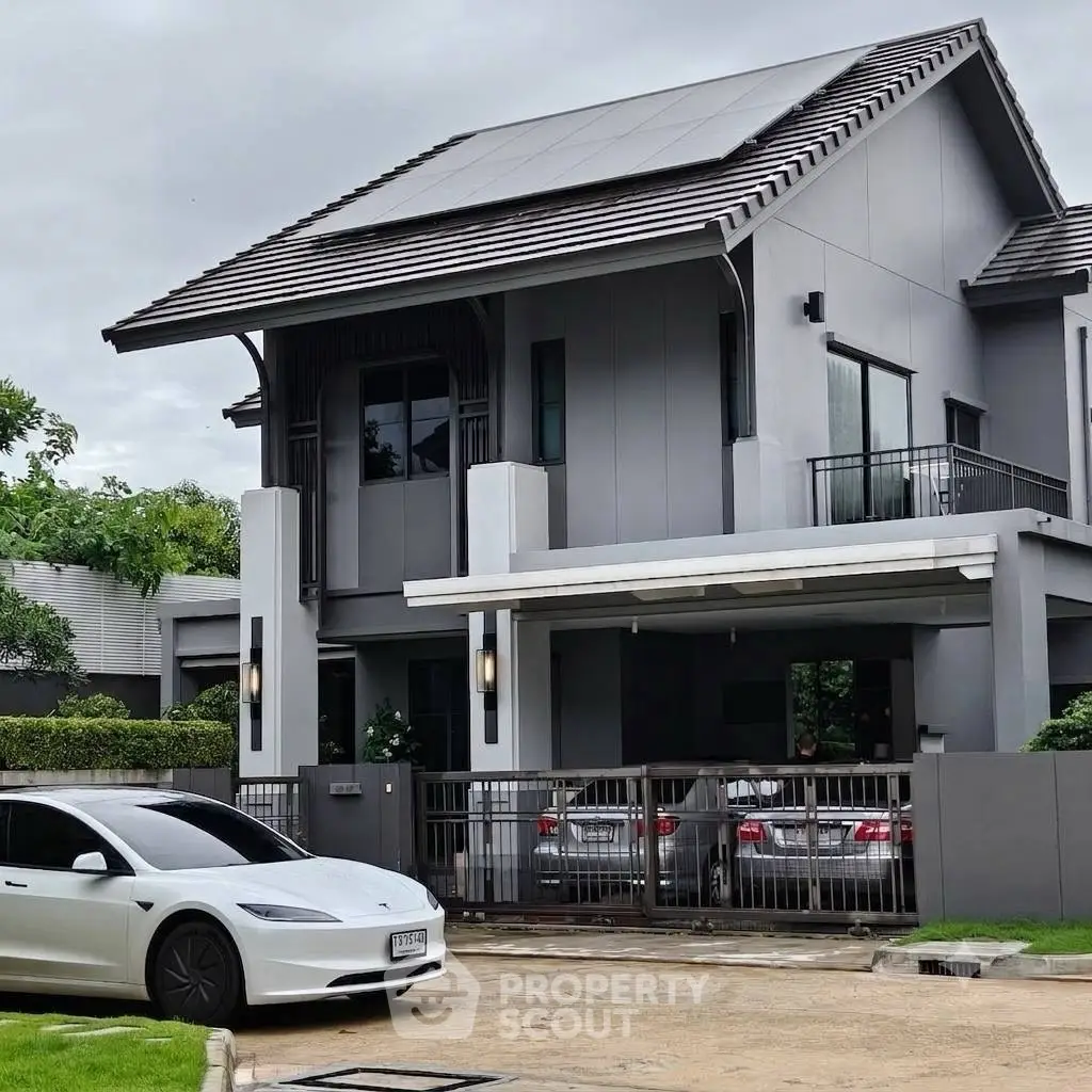 Modern two-story house with solar panels and sleek design, featuring a spacious driveway and lush greenery.