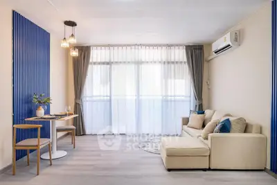 Modern living room with stylish decor, cozy sofa, dining area, and large windows for natural light.