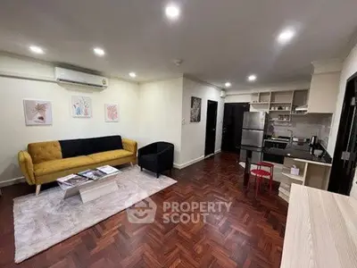 Stylish living room with parquet flooring and modern kitchen in open layout.