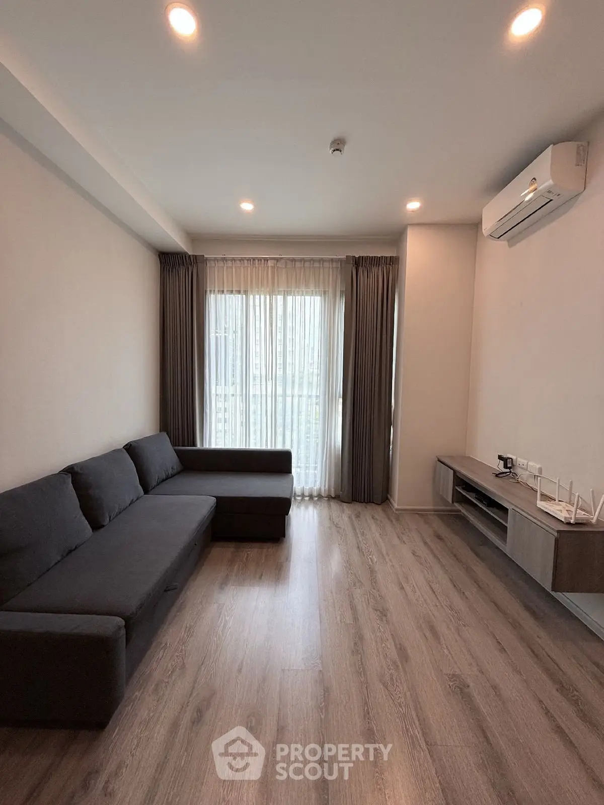Modern living room with sleek wooden flooring and large window for natural light.