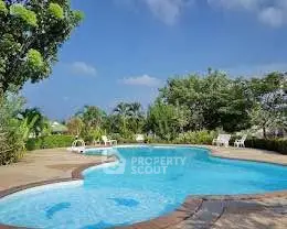 Stunning outdoor pool area with lush greenery and clear blue skies, perfect for relaxation and leisure.