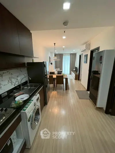 Modern open-layout kitchen and living area with sleek appliances and wooden flooring.