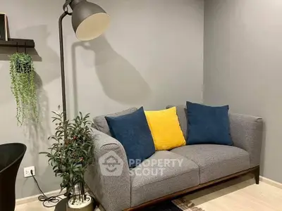 Cozy living room with modern gray sofa, vibrant cushions, and stylish floor lamp.