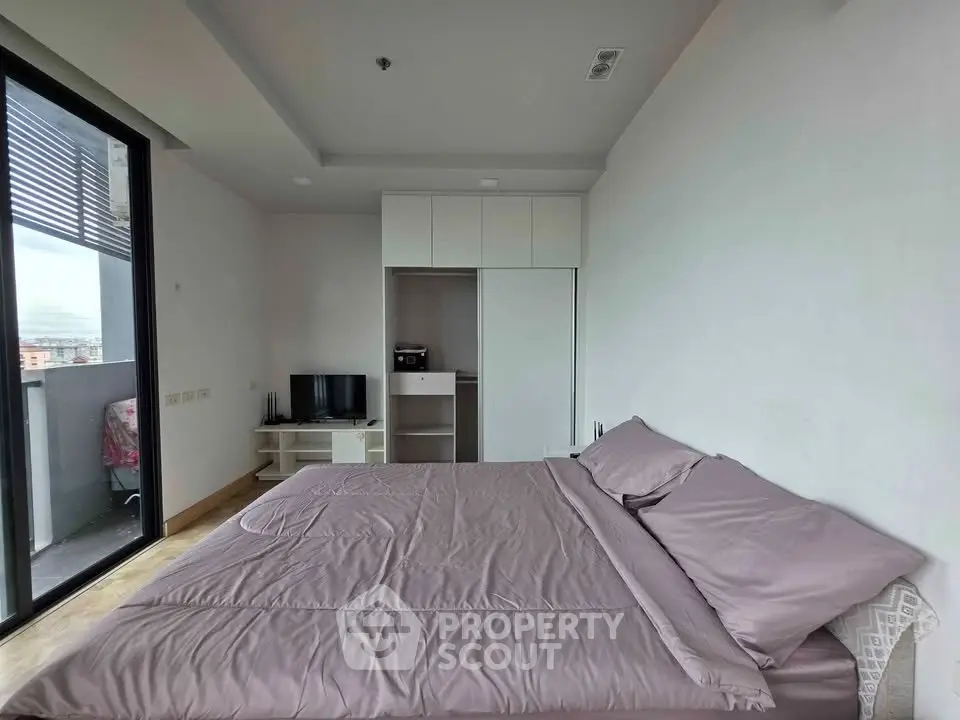 Spacious bedroom with modern decor and balcony access in a stylish apartment.