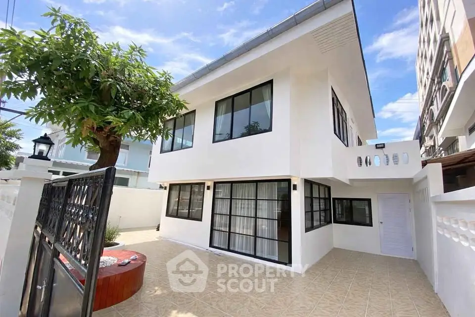 Modern two-story white house with large windows and spacious tiled courtyard.
