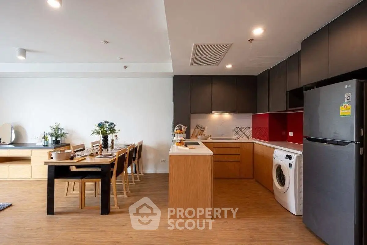 Modern open-plan kitchen with dining area, featuring sleek cabinetry and integrated appliances.