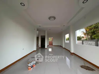 Spacious unfurnished living room with large windows and glossy tiled floors in a modern home.