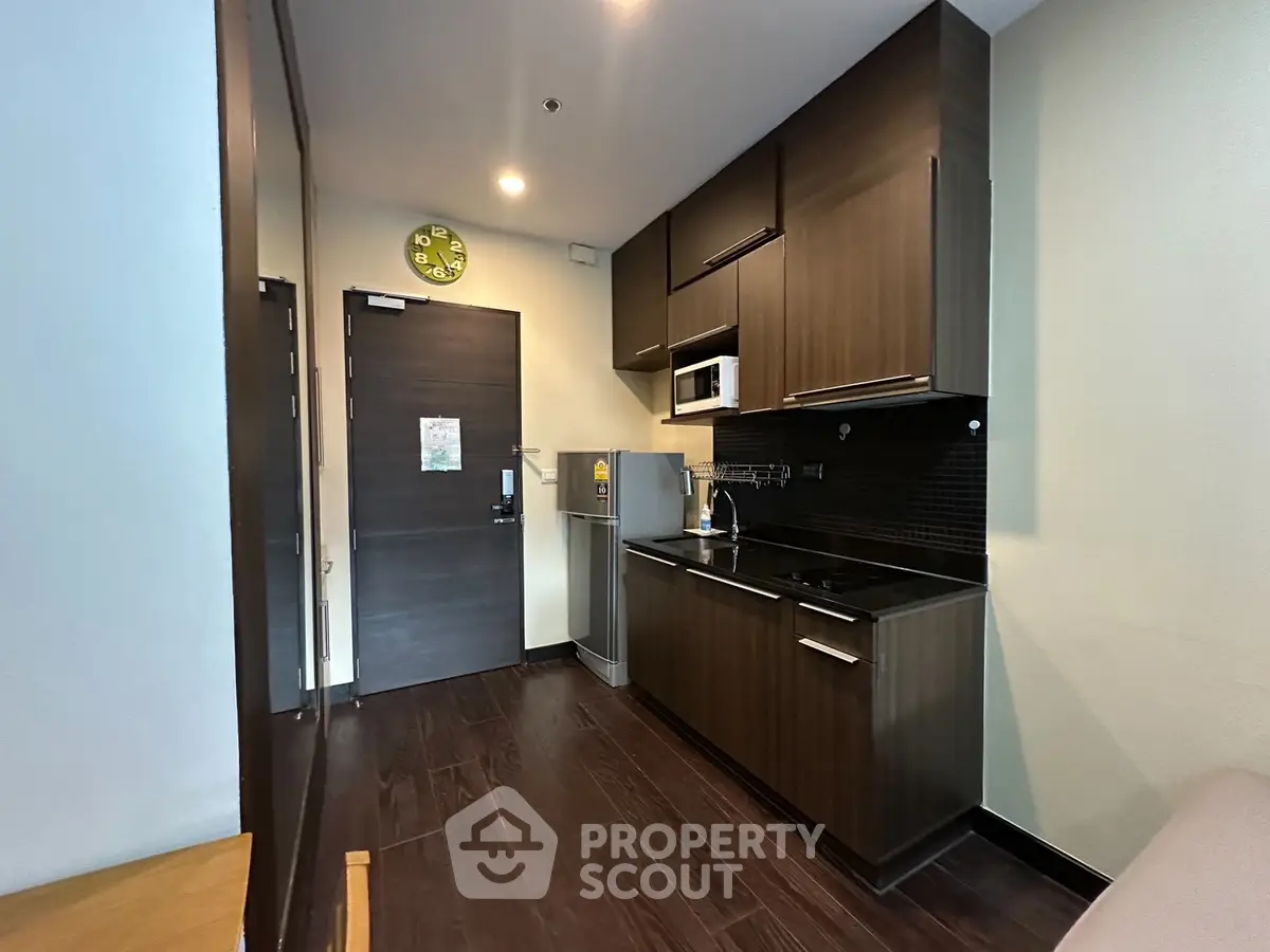 Modern kitchen with dark wood cabinets and sleek appliances in a cozy apartment.