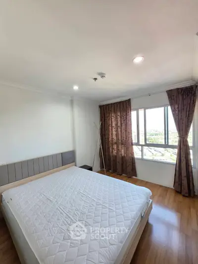 Spacious bedroom with large window offering stunning city views