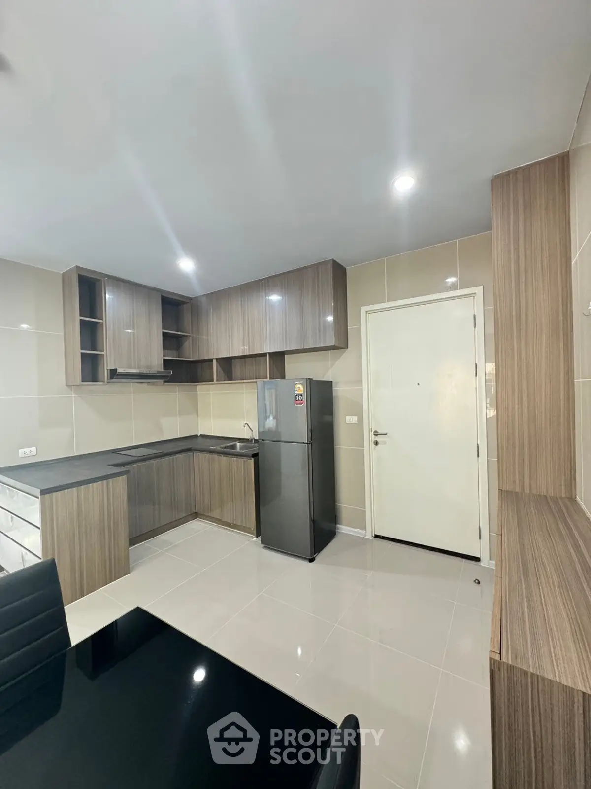 Modern kitchen with sleek cabinetry and stainless steel fridge in a contemporary apartment.