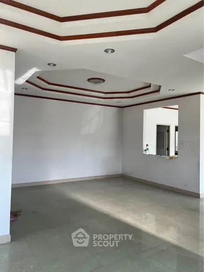 Spacious empty room with elegant ceiling design and tiled flooring, perfect for customization.