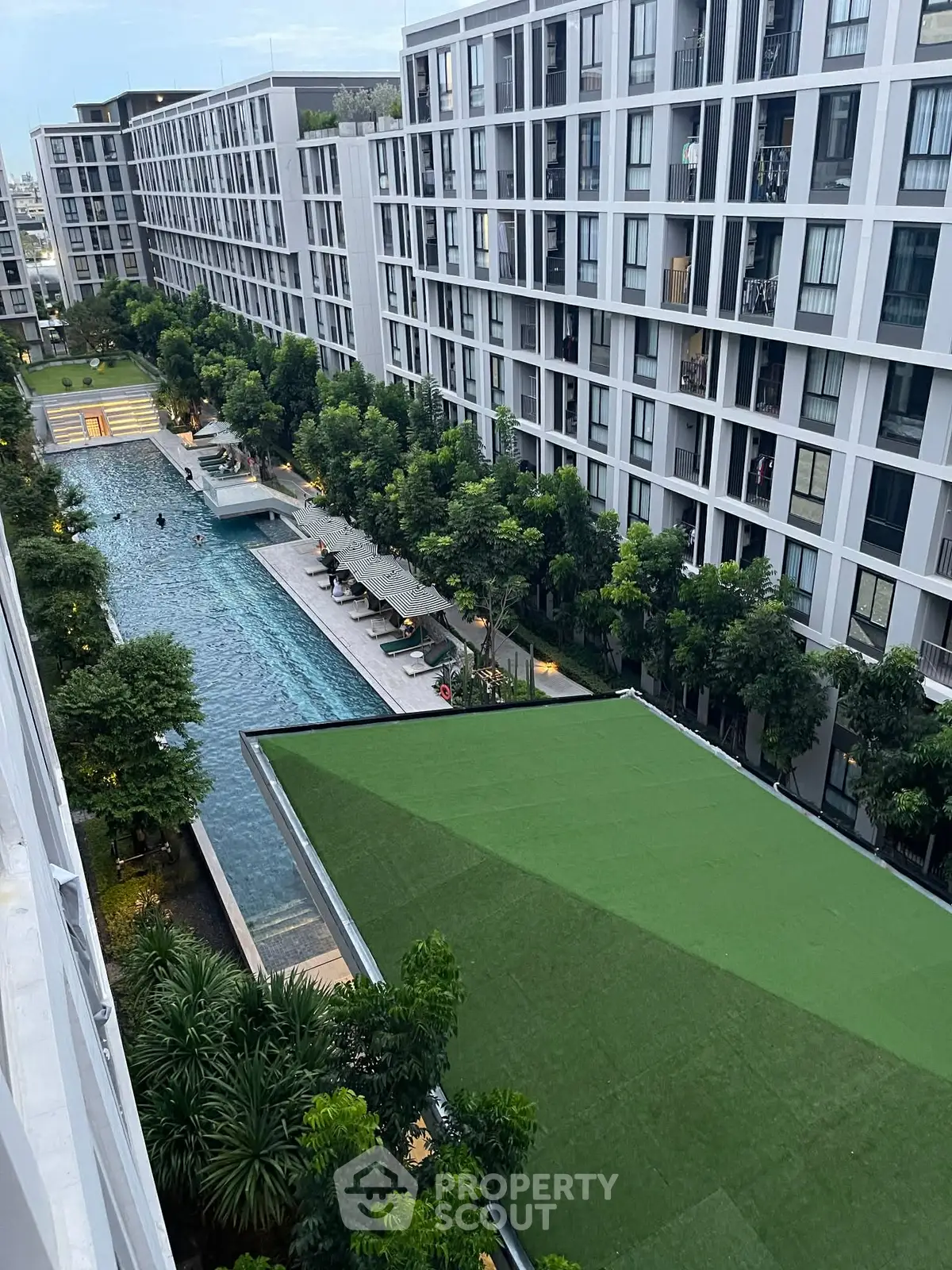 Modern apartment complex with lush greenery and inviting swimming pool view.