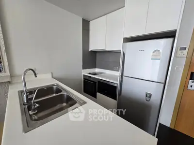 Modern kitchen with sleek white cabinets, stainless steel appliances, and a compact layout.