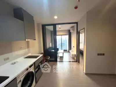 Modern apartment interior with open kitchen and living area, featuring sleek appliances and city view.