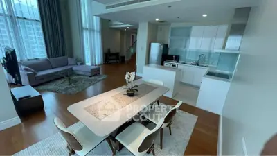 Spacious modern living room with open kitchen and dining area, featuring elegant decor and natural light.