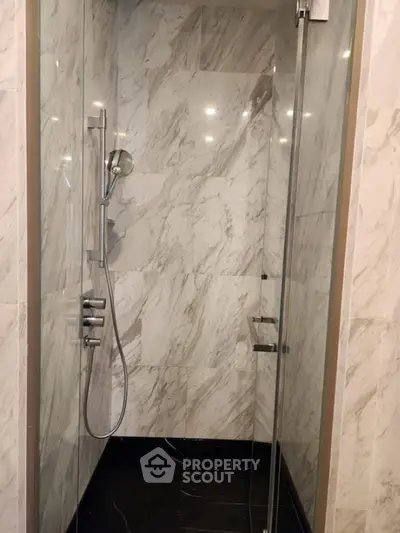 Luxurious marble-tiled shower with modern fixtures in a high-end bathroom.