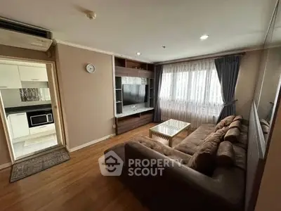 Cozy living room with plush sofa and entertainment unit, adjacent to modern kitchen.