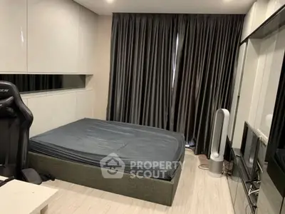 Modern bedroom with sleek design, featuring a comfortable bed, gaming chair, and stylish curtains.