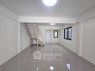 Spacious modern living room with sleek tile flooring and staircase, perfect for contemporary living.
