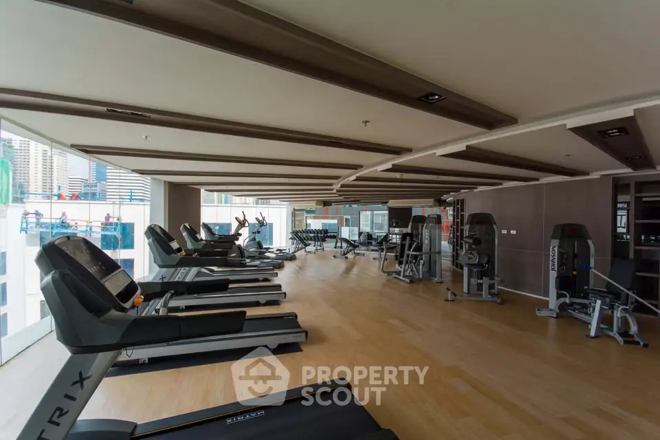 Spacious modern gym with city view in luxury residential building.